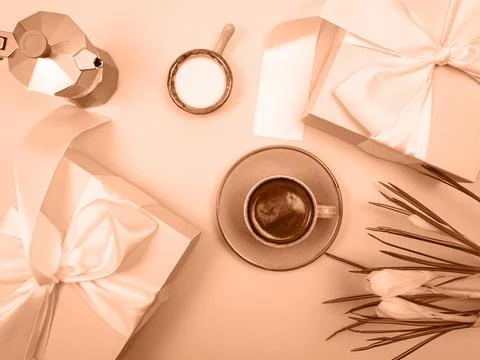 There is a coffee pot on the table, a cup of coffee, a notebook and flowers. The Stock Photos