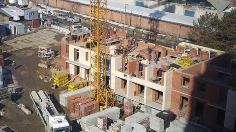 There is a construction of a new house, builders lay bricks, using a crane and Stock Footage 73855528