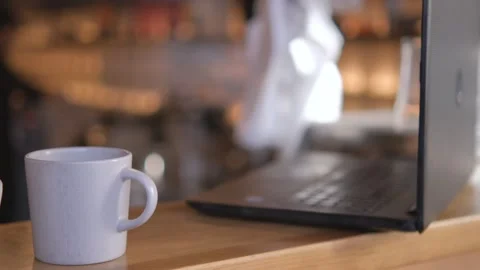 There is a cup and a laptop on the bar counter in a coffee shop. Stock Footage 244052422
