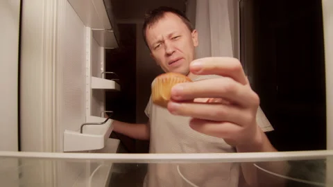 There is a cupcake in the fridge, a man opens the fridge and takes the cupcake Stock Footage 144890041