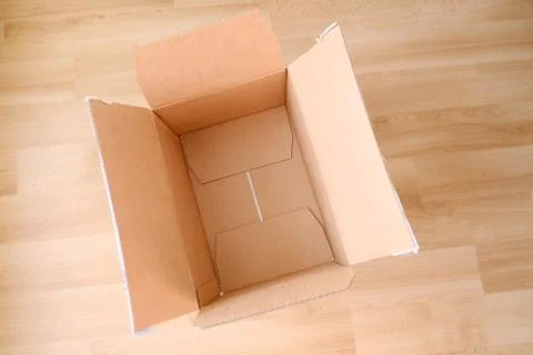 There is an empty open cardboard box on the floor, concept of mailing, packag Stock Photos