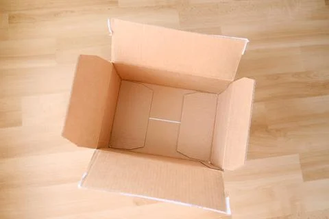 There is an empty open cardboard box on the floor, concept of mailing, packag Stock Photos