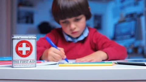 There is a first-aid kit on the table, in the background the boy draws Stock Footage 116536521