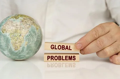 There is a globe on a white reflective surface, in the hands of wooden bloc.. Stock Photos