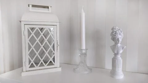 There is a lantern with a candlestick and a statuette on the fireplace Stock Photos