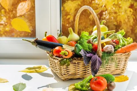 There is a large basket of vegetables by the window. A set of vegetables vege Stock Photos