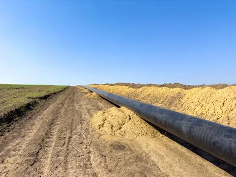 There is a large pipe running through a vast dirt field area Stock Photos