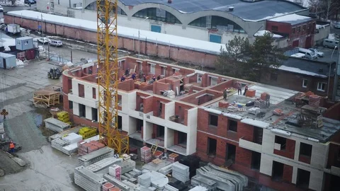There is a multi-apartment building made of bricks. A construction crane loads Stock Footage 73964574