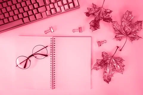 There is a notebook, a keyboard, maple leaves on the table. The color of the Stock Photos
