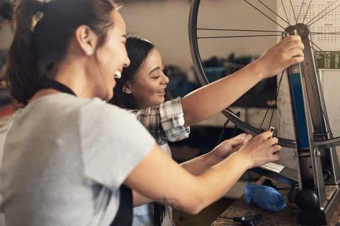 There is nothing too broken. two young female workers fixing a bike at a bicycle Stock Photos
