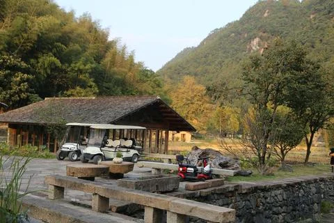 There is an old thatched house with two white golf carts parked at its entr.. Stock Photos