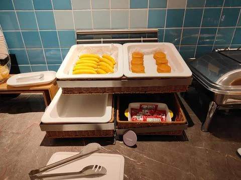There is one rectangular tray with yellow sausages and another white wicker.. Stock Photos