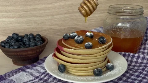 There is a plate with pancakes on the table and they pour honey on top Stock Footage 247233450