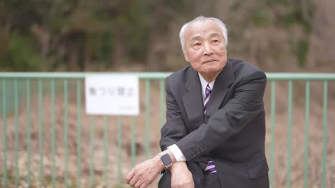 There is plenty of greenery in the spring noon park in Japan. A Japanese man Vídeo Stock 307378459