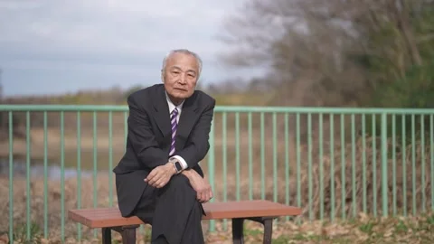 There is plenty of greenery in the spring noon park in Japan. A Japanese man Vídeo Stock 307378634
