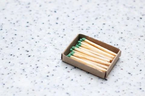 There is a rectangular box of matches with green tips placed on a table Stock Photos