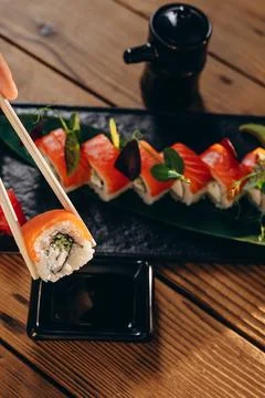 There is a rectangular decorated plate of sushi on the wooden table. Stock Photos