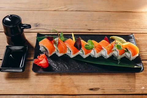 There is a rectangular plate of sushi on the wooden table. Stock Photos