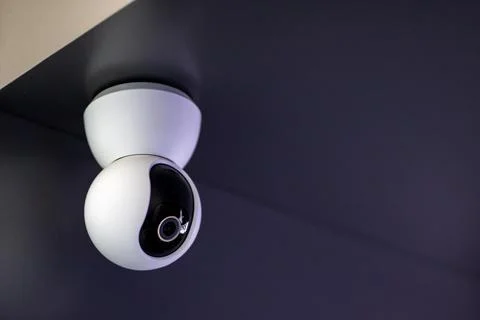There is a security camera that is hanging from the ceiling in a dark room Foto stock