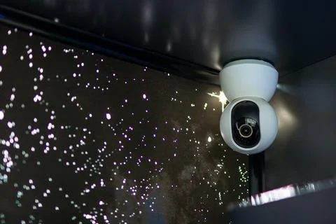 There is a security camera that is hanging from the ceiling in a dark room Foto stock