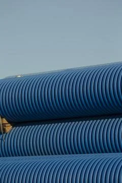 There is a stack of blue plastic pipes placed against a clear blue sky Stockfoto's