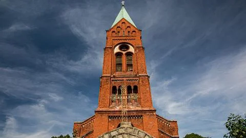 There stands a large brick tower which has a cross on the top of it Stock Photos
