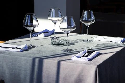 There is a table with three wine glasses and silverware set on it Stock Photos