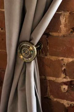 There is a wall of red brick. her round holder keeps the grey curtain Stock Photos