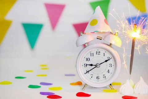 There is a white alarm clock on the table, it shows 9 o'clock, next to it is Stock Photos