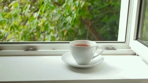 There is a white ceramic cup with hot tea on the windowsill. Stock Footage 140267876