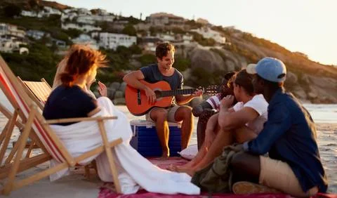 Theres always an entertainer in the group. a man playing the guitar while Stock Photos