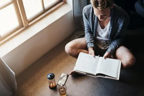 Theres nothing wrong with being a book worm. High angle shot of a young man Stock Photos