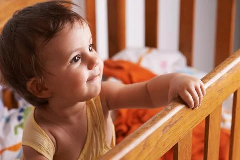 Theres so much world to explore. A cute little girl standing up in her crib. Foto stock