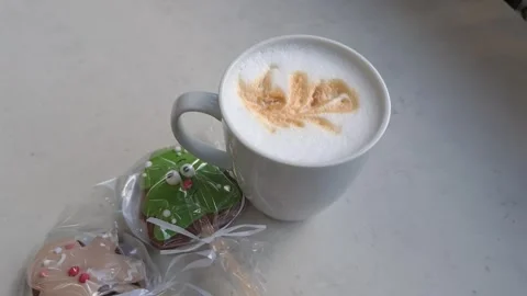 There's a white cup of cappuccino on the table with two gingerbread cookies Stock Footage 323165455