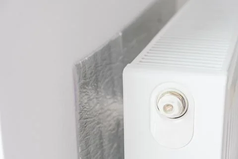 Thermal insulation panel positioned behind radiator to reflect heat into room Stock Photos