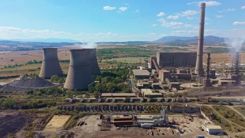 Thermal power plant rises over rural fields, with cooling towers, smokestack and Video stock 345972706