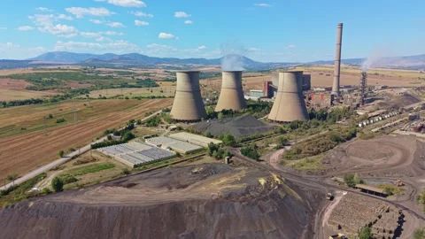 Thermal power plant rises over rural fields, with cooling towers and smokestacks Stock Footage 345972709