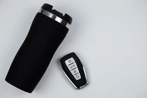 A thermocup and a key with automatic buttons in black with metal inserts lie on Stock Photos