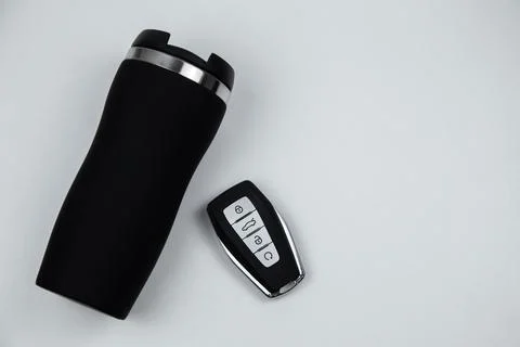 A thermocup and a key with automatic buttons in black with metal inserts lie on Foto stock