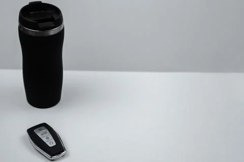 A thermocup and a key with automatic buttons in black and with metal inserts Stock Photos