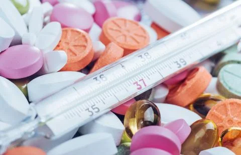 Thermometer and different colored types of pills. Medical health or drugs con Stock Photos
