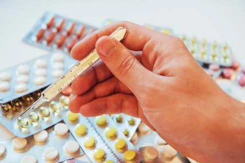 Thermometer and different colored types of pills. Medical health or drugs con Stock Photos