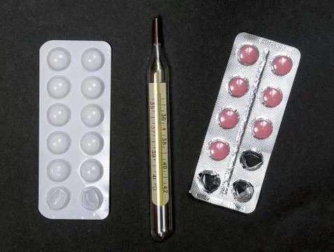  Thermometer and pills on a black background Stock Photos