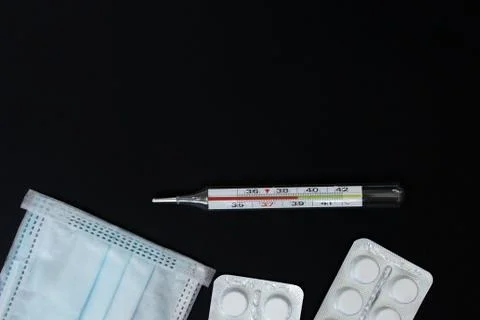 Thermometer and tablets on a black background Stock Photos