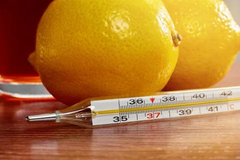 Thermometer on the background of lemons Stock Photos