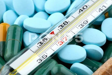 Thermometer on blue pills and colorful capsules. Medicine Stock Photos