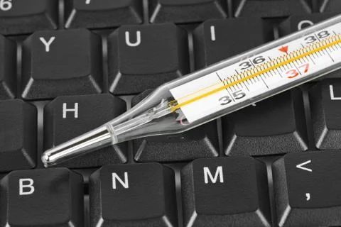 Thermometer on computer keyboard Stock Photos