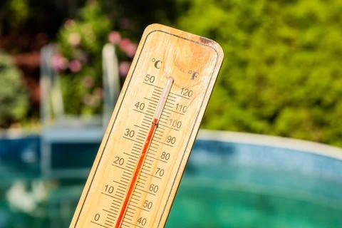 Thermometer displaying high summer temperature on a swimming pool background Foto stock