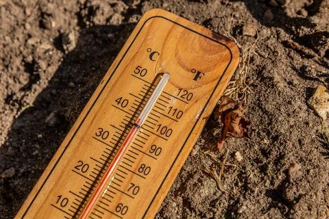 Thermometer displaying high summer temperature on a dry dirt background Foto stock