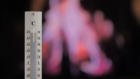 Thermometer with a fire in the background shows increasing temperature. Stock Footage 202130904